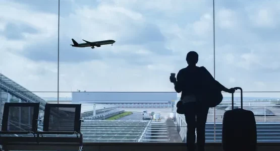 Voyageur avec valise observant un avion depuis un terminal d’aéroport